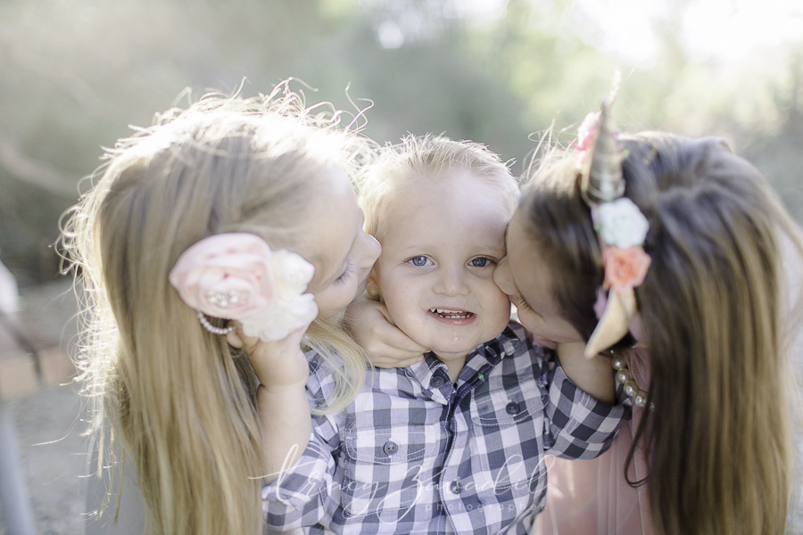 sisters giving their brother a kiss